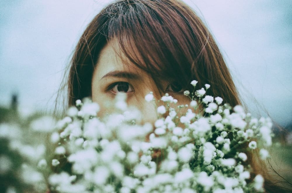 花で口元を隠す女性